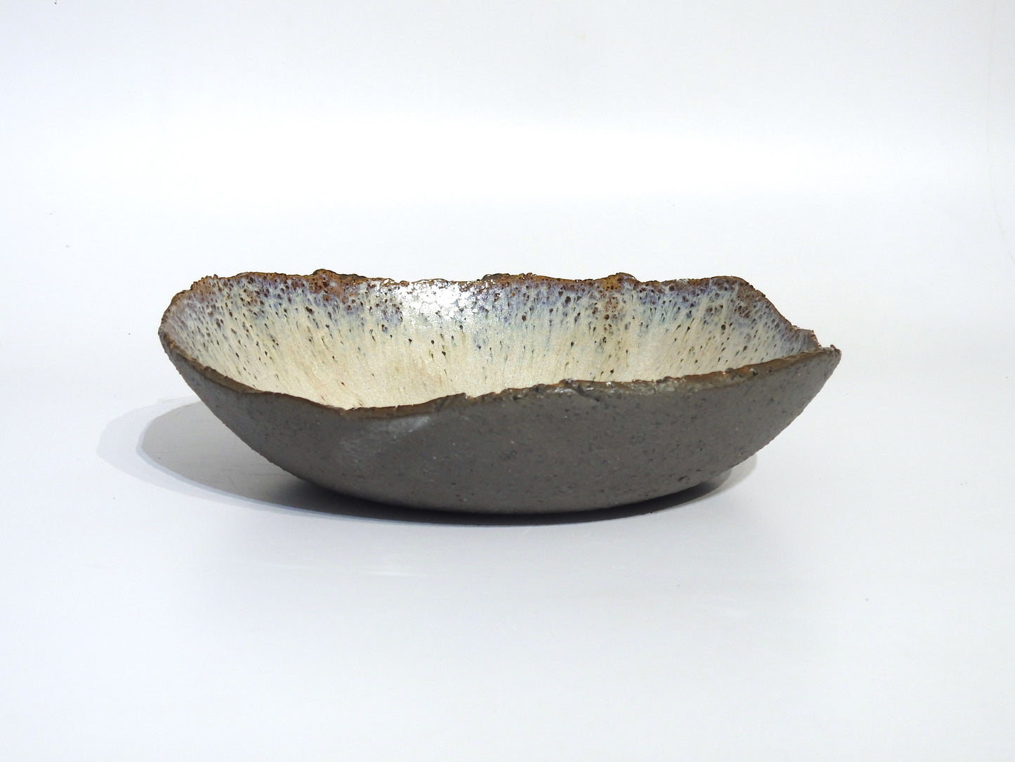 The STONE BIG SALAD BOWL is a handmade ceramic piece, 27.5 cm in diameter, with a rough dark exterior and smooth light interior, shown against a plain white background.