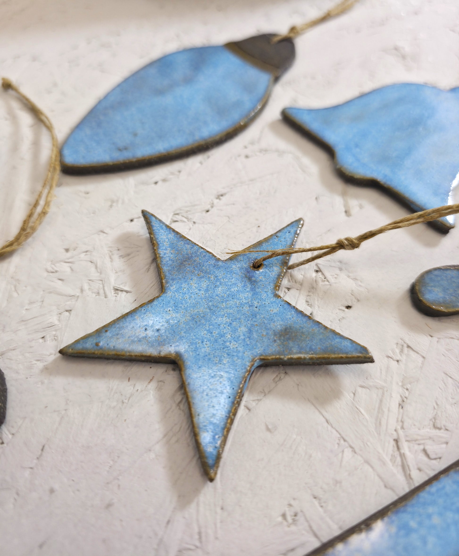 Box 2 features handcrafted blue ceramic ornaments with twine loops for hanging, including a central star shape, displayed on a textured white surface—ideal for Christmas gifting.
