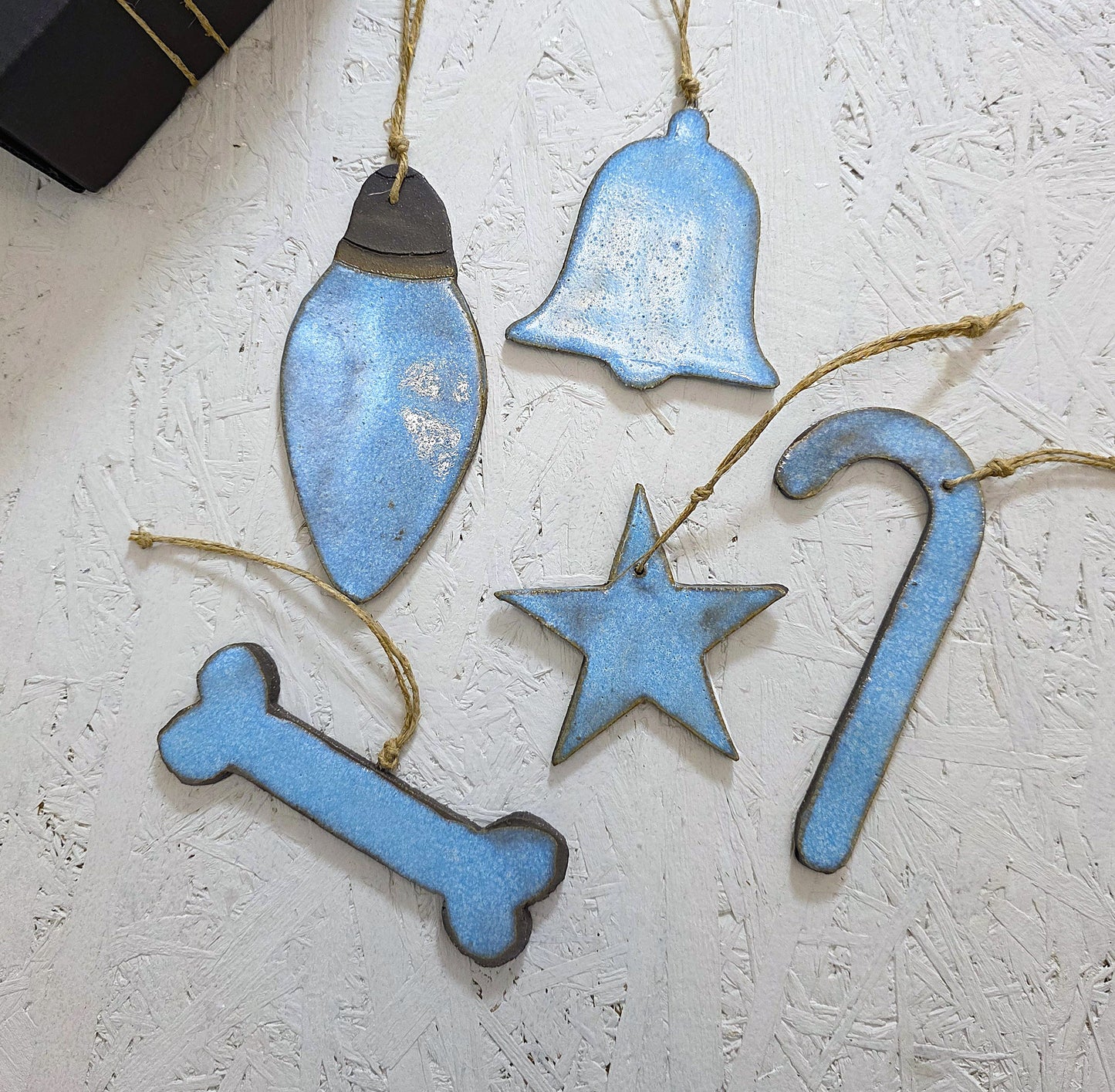 Box 2 features five handcrafted ceramic ornaments—a light bulb, bell, star, candy cane, and bone—hung on twine and displayed on a textured white surface, making them perfect for Christmas gifting.
