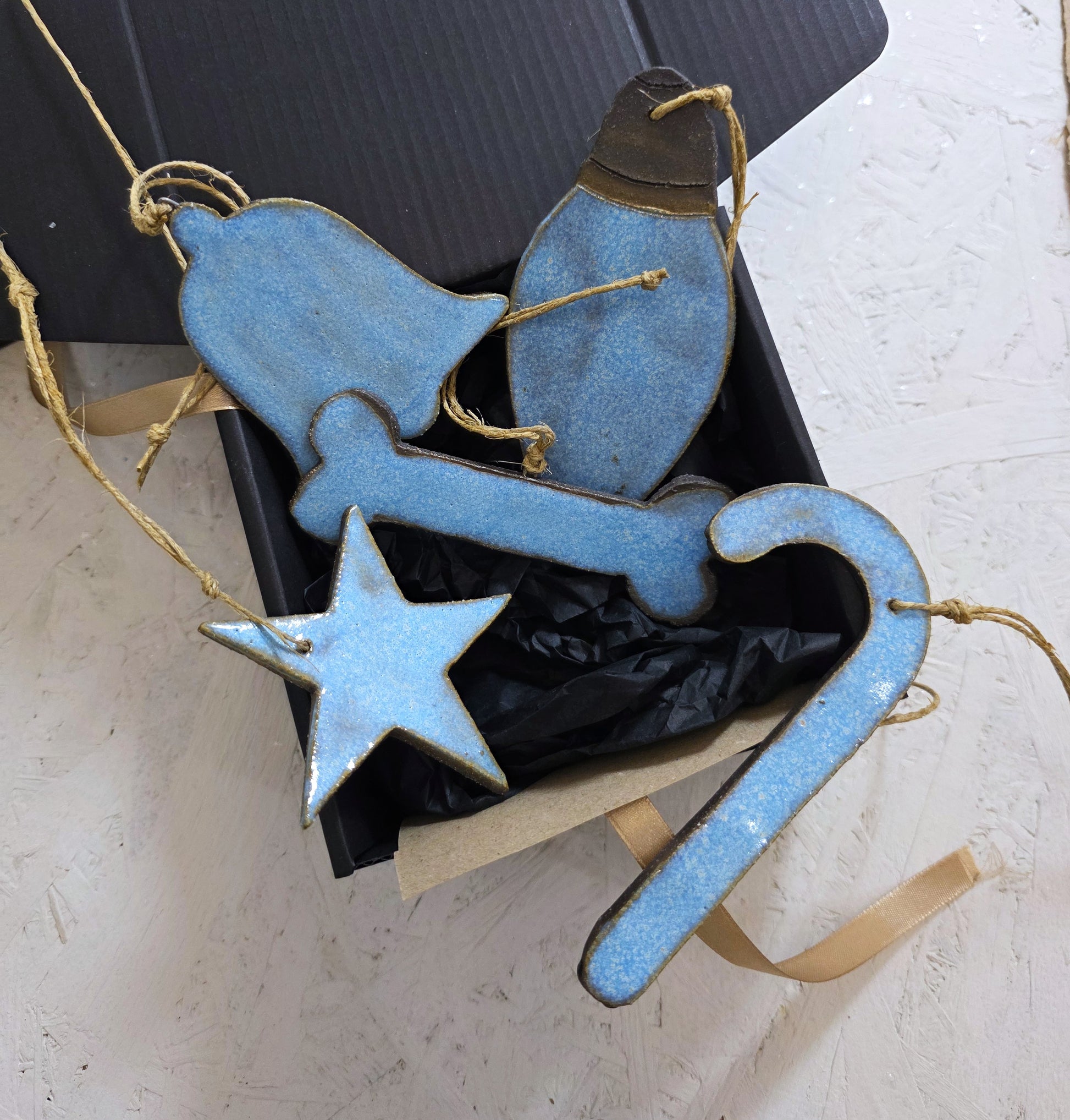 Box 2 features handcrafted ceramic ornaments—bell, bird, bone, star, and candy cane—each tied with raffia and nestled in black tissue paper. Presented in a luxury box, it's the perfect Christmas gift.