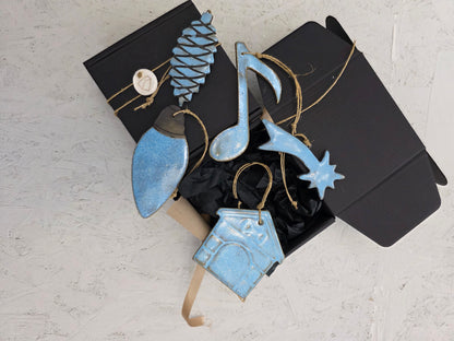 Box 3 is a luxury gift box with black tissue paper, featuring handcrafted ceramic ornaments—blue pinecone, musical note, shooting star, house, and bird—tied with twine and ideal for Christmas gifting.