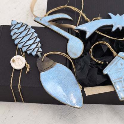 Box 3 features handcrafted ceramic ornaments—pinecone, musical note, star, lightbulb, and house—each glazed in light blue and presented on a black luxury gift box with twine. An elegant choice for Christmas gifting.