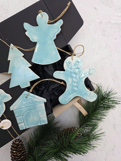 Box 4 is a luxury gift box with handcrafted light blue ceramic ornaments—angel, tree, gingerbread person, and house—nestled among pine branches and pinecones. It’s the perfect elegant Christmas gift.