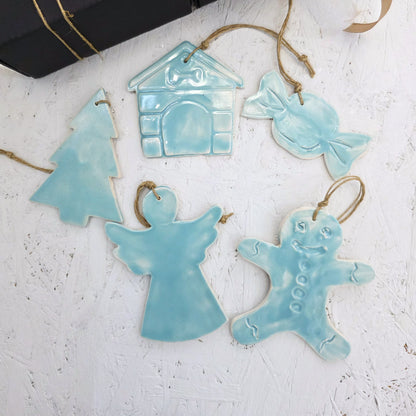 Box 4 includes five handcrafted light blue ceramic ornaments—house, candy, tree, angel, and gingerbread person—each with a twine loop, arranged on a white textured surface. Perfect for Christmas gifting.