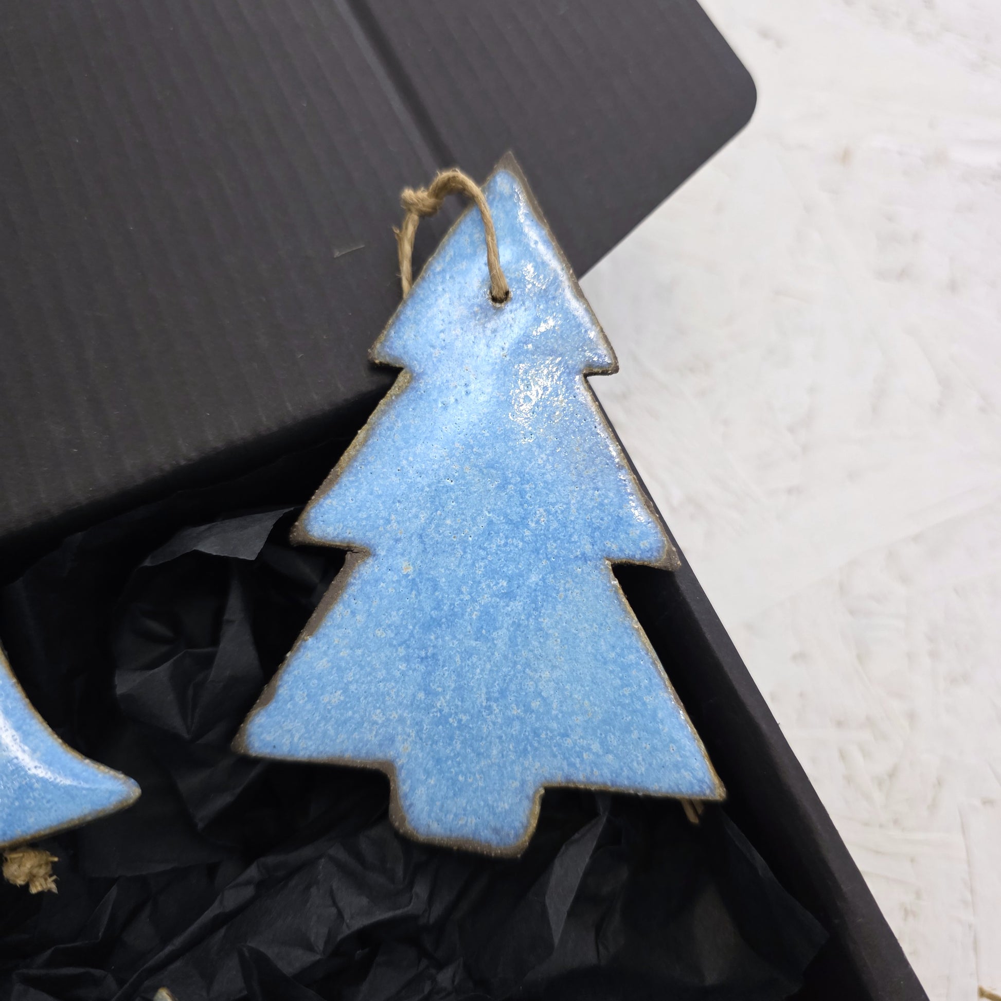 Box 5 is a blue handcrafted ceramic ornament with a twine loop, presented on black tissue paper inside a luxury gift box—perfect for Christmas gifting.