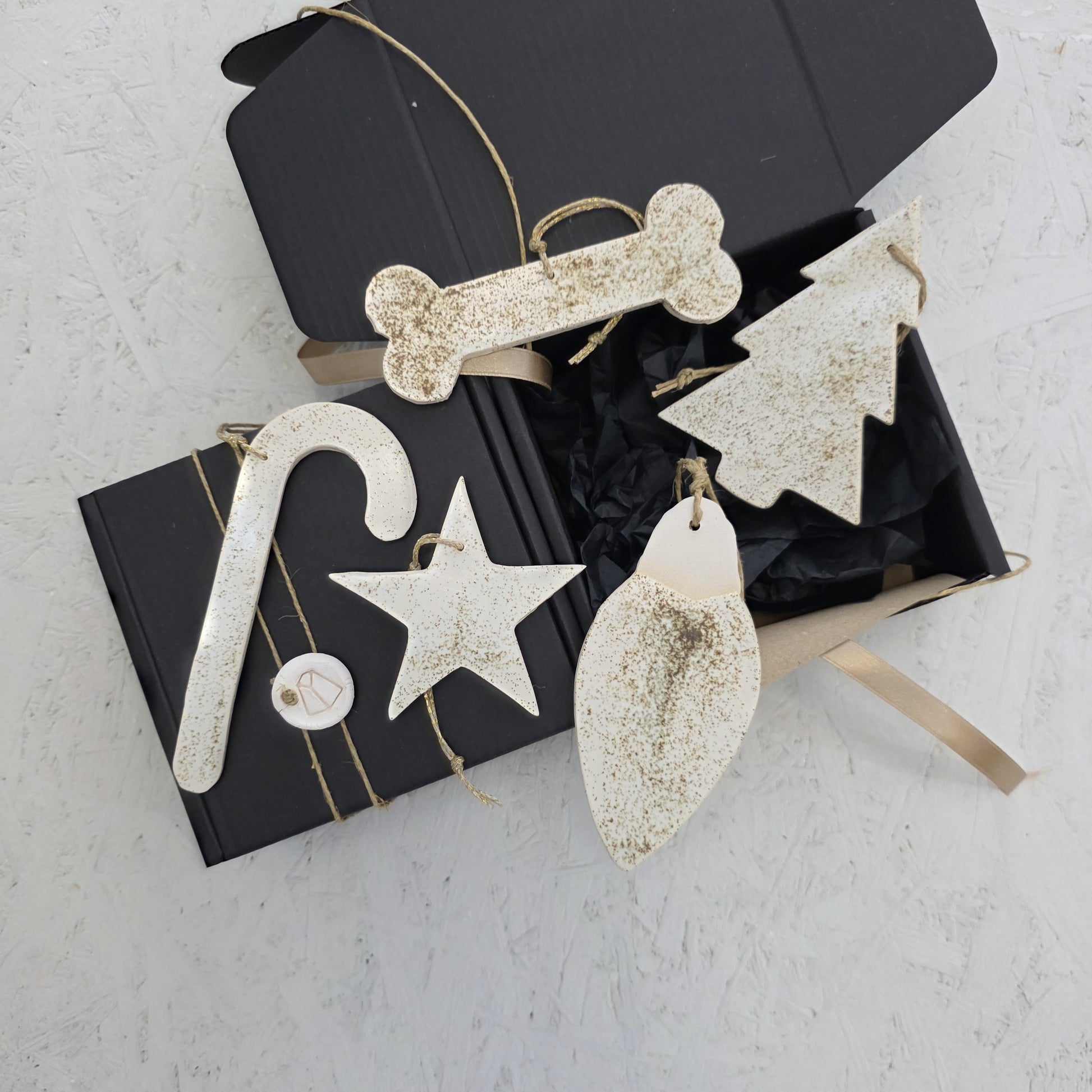 Box 7 features cream-colored, textured ceramic ornaments in festive shapes, presented in a handcrafted gift box with tan ribbon. Perfect for Christmas gifting, these elegant accents enhance any holiday décor.