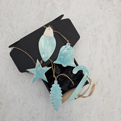 Box 9 by Magma Lab is a luxury gift set featuring five glossy ceramic ornaments—a shell, bell, star, Christmas tree, and candy cane—each tied with twine and beautifully presented for perfect holiday gifting.
