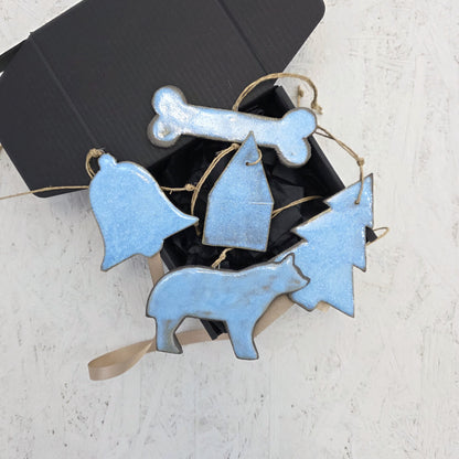 Box 8 by Magma Lab is a limited edition black handcrafted gift box with black tissue, featuring five luxury ceramic ornaments—bone, bell, house, tree, and wolf—each tied with twine and presented on a white textured surface.