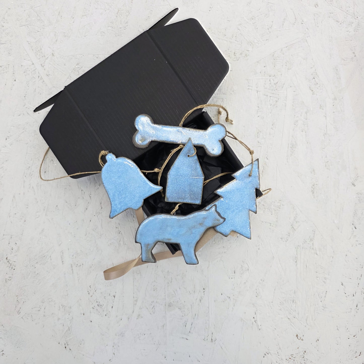 Box 8 by Magma Lab is a limited edition black box featuring luxury ceramic ornaments—bone, bell, house, tree, and animal shapes—artfully arranged on a light textured surface.