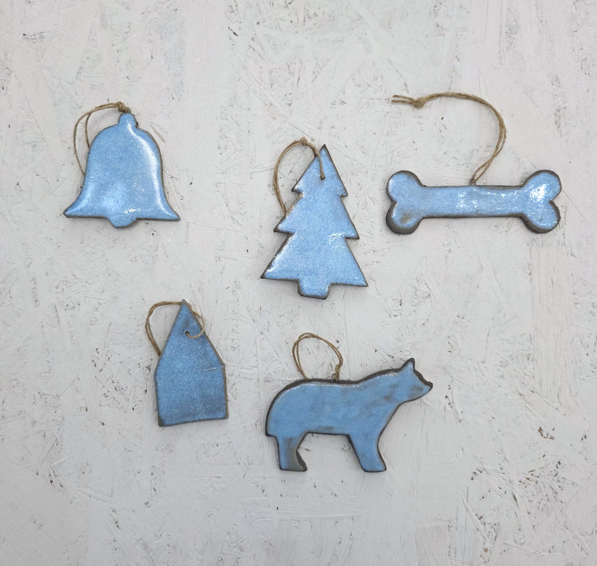 The Magma Lab Box 8 features five blue luxury ceramic ornaments—bell, tree, bone, house, and bear—with twine loops, beautifully arranged on a light textured surface and presented in a handcrafted gift box. Limited edition.