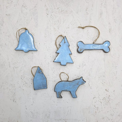 Box 8 by Magma Lab features five blue luxury ceramic ornaments—bell, Christmas tree, bone, house, and animal shapes—with twine loops against a white background. A perfect limited edition handcrafted gift box.