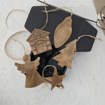 Box 10 by Magma Lab features five handcrafted ceramic ornaments—a doghouse, bauble, Christmas tree, angel, and star—arranged on black tissue in a luxury gift box, making it an ideal Christmas gift.