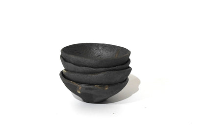 Three SOIL SMALL DIP BOWLs, crafted from black ceramic with a rough matte finish, highlight handmade stoneware and timeless Greek craftsmanship. The bowls are stacked unevenly against a plain white background.