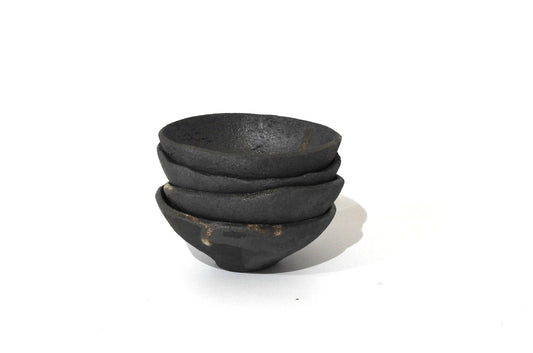 Three SOIL SMALL DIP BOWLs, crafted from black ceramic with a rough matte finish, highlight handmade stoneware and timeless Greek craftsmanship. The bowls are stacked unevenly against a plain white background.