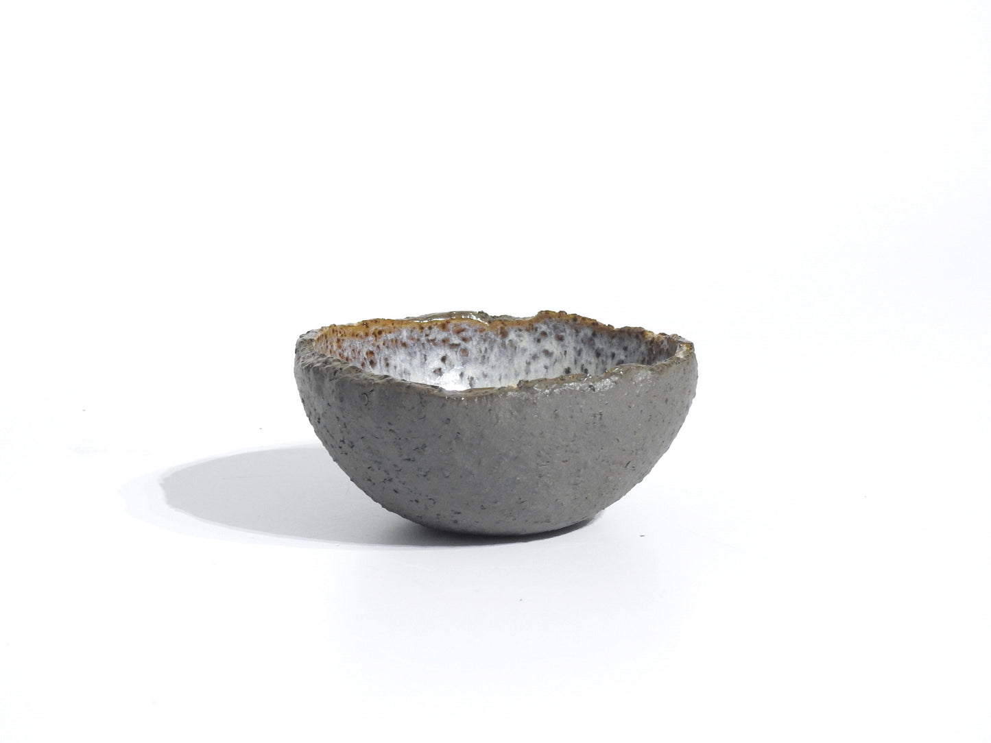 The STONE DIP BOWL, a small handmade piece inspired by Greek pottery with a textured gray exterior and glazed white-speckled interior, is displayed on a plain white background.