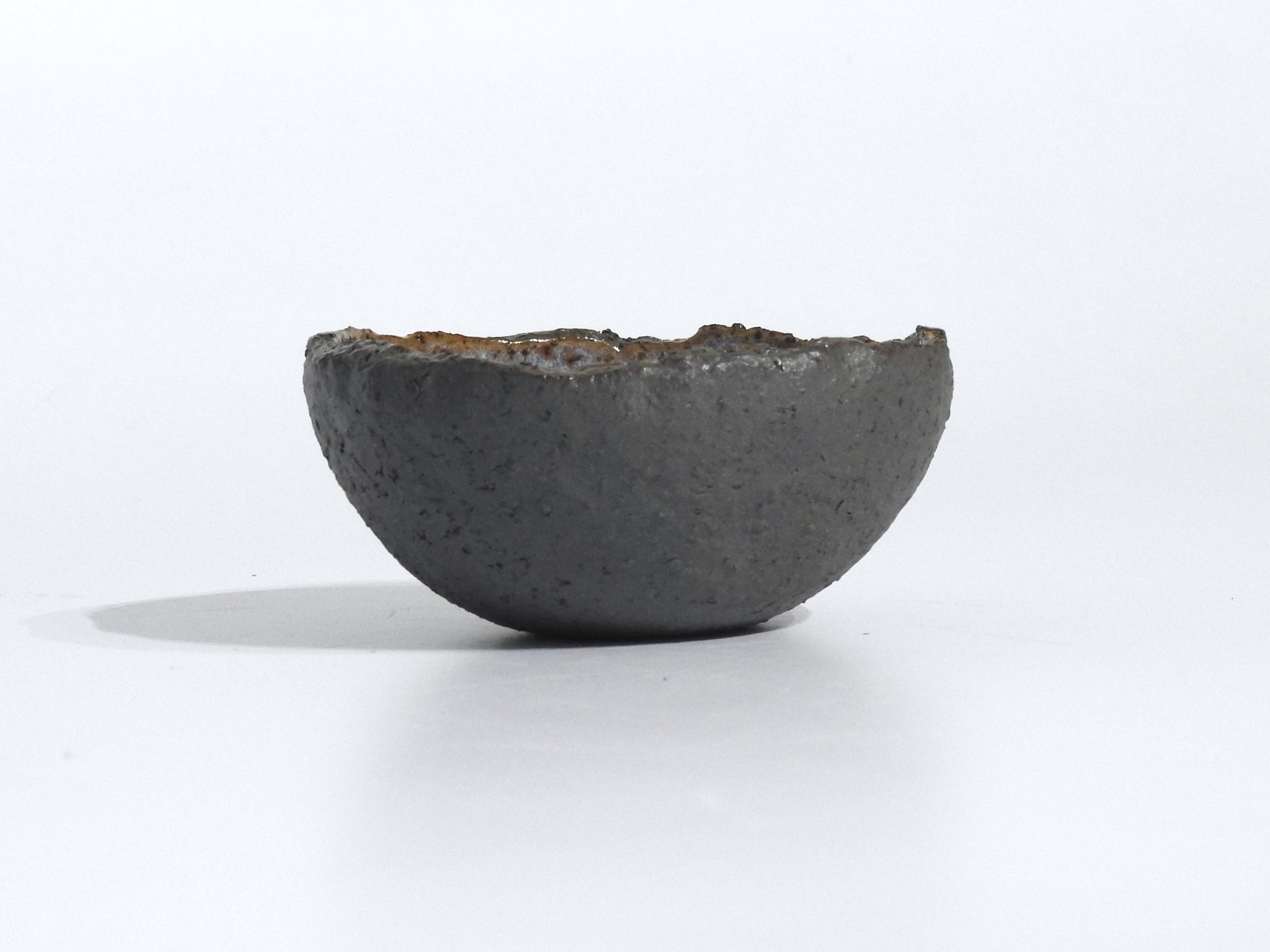 The STONE STARTER BOWL, a handmade dark gray half-sphere with an uneven rim, rests on a white surface against a plain white background.