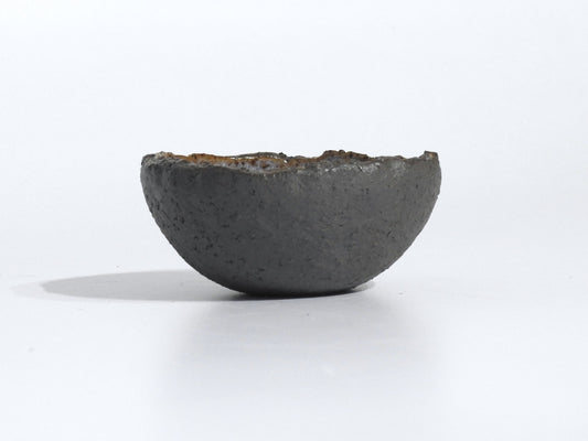 The STONE STARTER BOWL, a handmade dark gray half-sphere with an uneven rim, rests on a white surface against a plain white background.