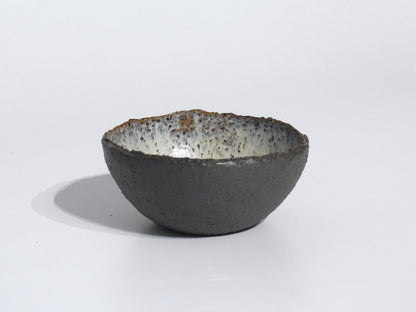 The STONE STARTER BOWL is a handmade serving bowl inspired by Greek pottery, with a rough dark gray exterior and a speckled white interior, shown on a plain white background.