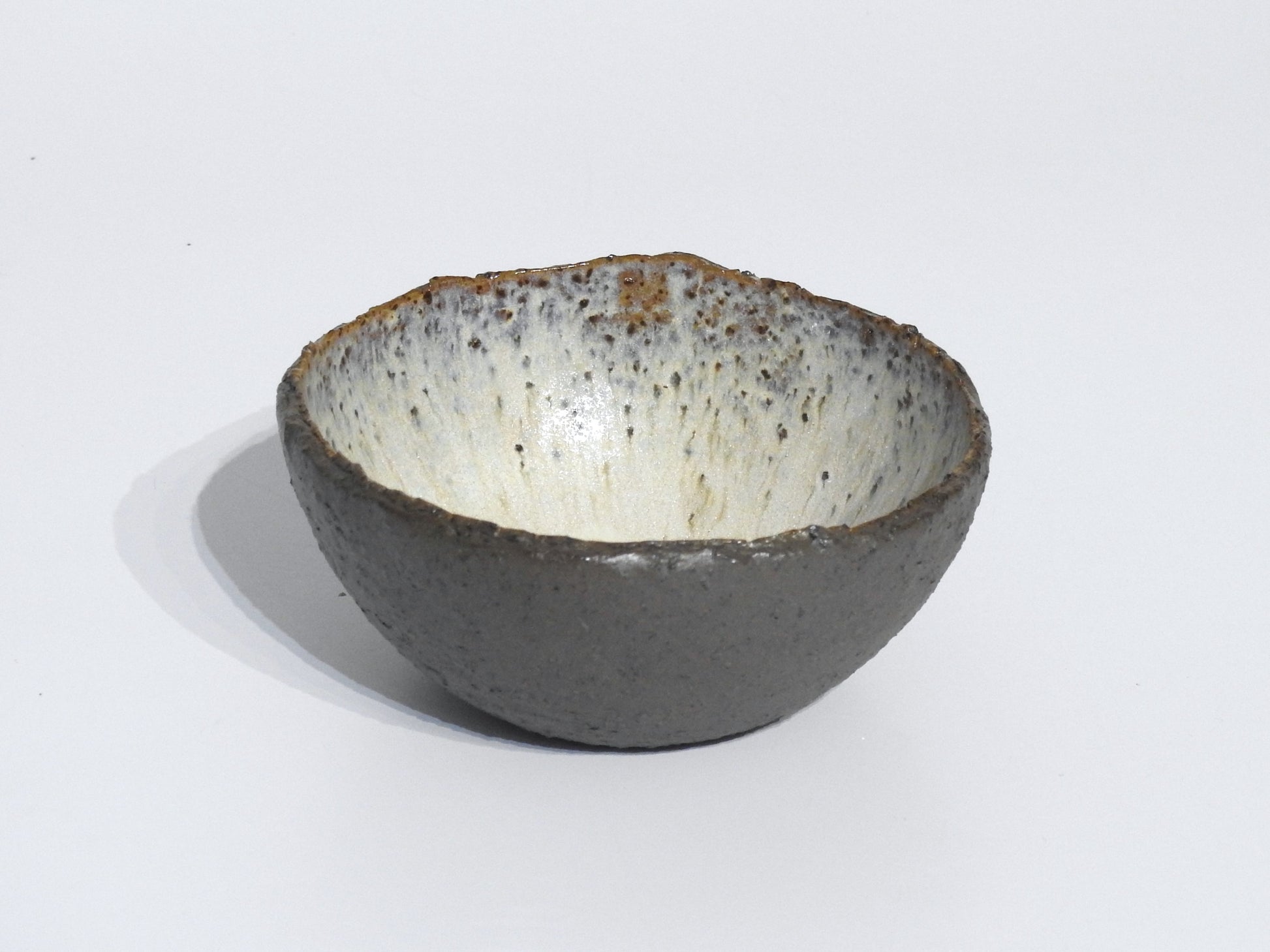 The STONE STARTER BOWL features a handmade design with a textured dark gray exterior and speckled off-white interior, inspired by Greek pottery, photographed against a plain white background.