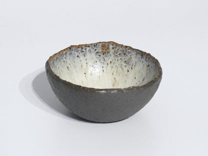 The STONE STARTER BOWL features a handmade design with a textured dark gray exterior and speckled off-white interior, inspired by Greek pottery, photographed against a plain white background.