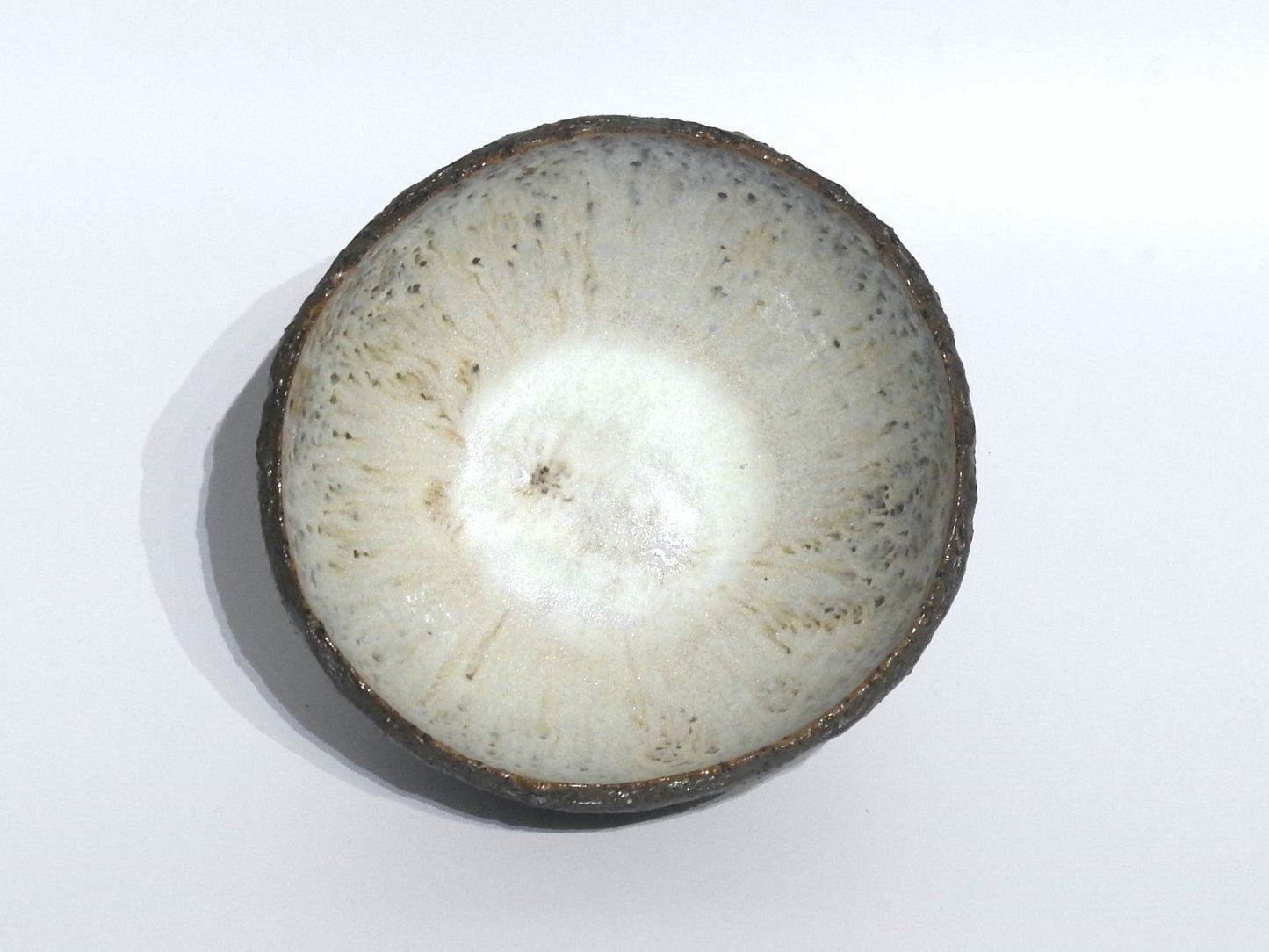 The STONE STARTER BOWL is a handmade stoneware bowl featuring Greek craftsmanship, a textured speckled white glaze, and a rough dark rim, shown photographed from above on a white background.