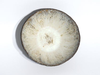 A cross-section of a round root vegetable with brown, rough skin and white, speckled interior sits ready for slicing beside the STONE SOUP BOWL, ideal for prepping in your 18 cm or small frying pan. Photographed on a plain white background.
