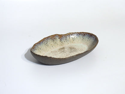 The STONE OVAL BOWL is handmade with a textured, earthy brown exterior and a lightly speckled off-white interior. It measures 24.5 cm long by 15.5 cm wide and is shown on a plain white background.