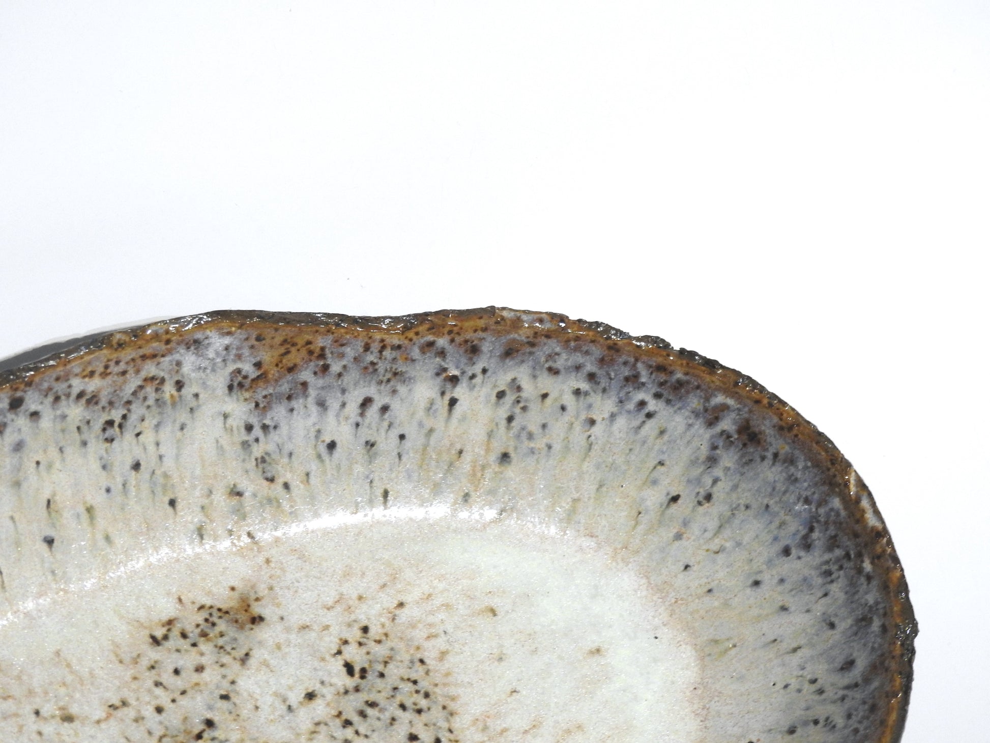 A close-up of the STONE OVAL BOWL's edge reveals its speckled, textured glaze in gray, white, and brown tones against a white background. Bowl diameter: 24.5 cm.