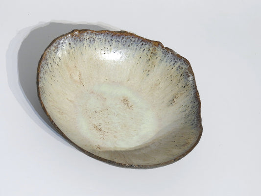 The STONE BIG SALAD BOWL is a handmade ceramic piece with an uneven rim, light beige glaze, and subtle blue speckles around the edge. It measures 7.5 cm high by 27.5 cm long and is shown on a plain white background.