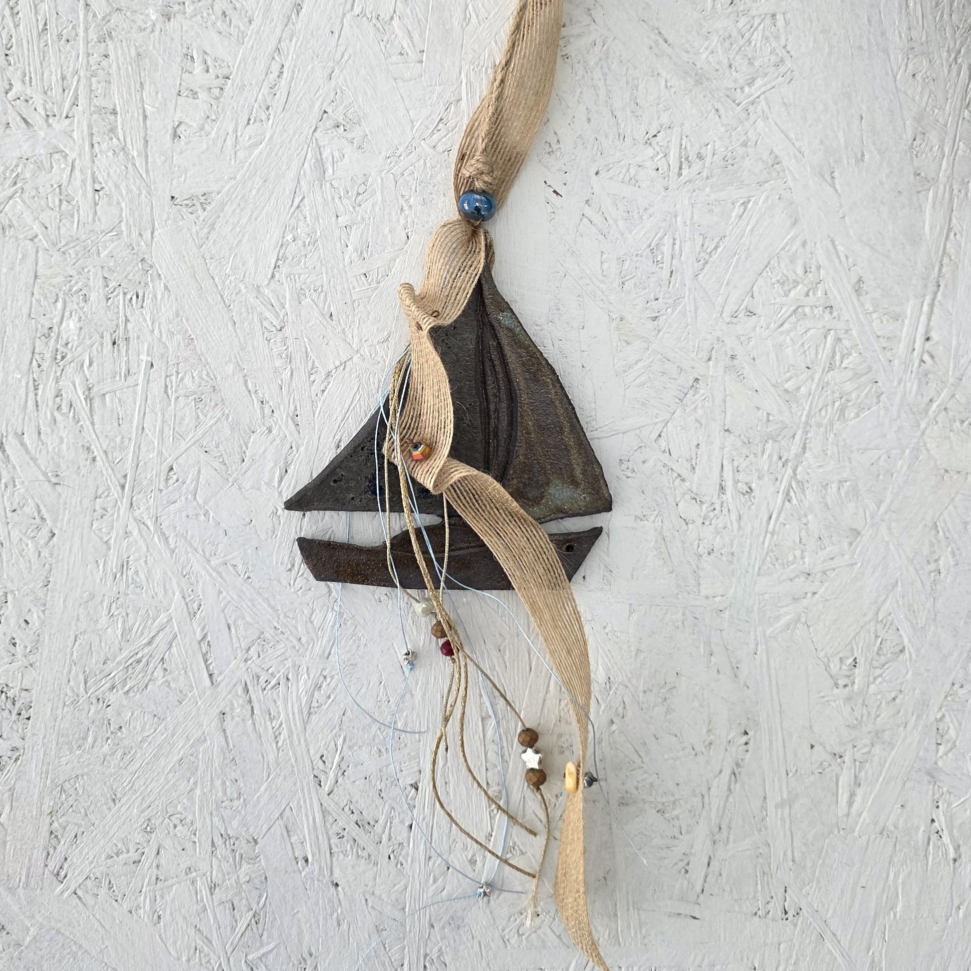 Decorative wall hanging with fabric and beads on a textured white background