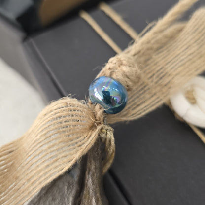 Close-up of a blue bead on a piece of burlap with a blurred background