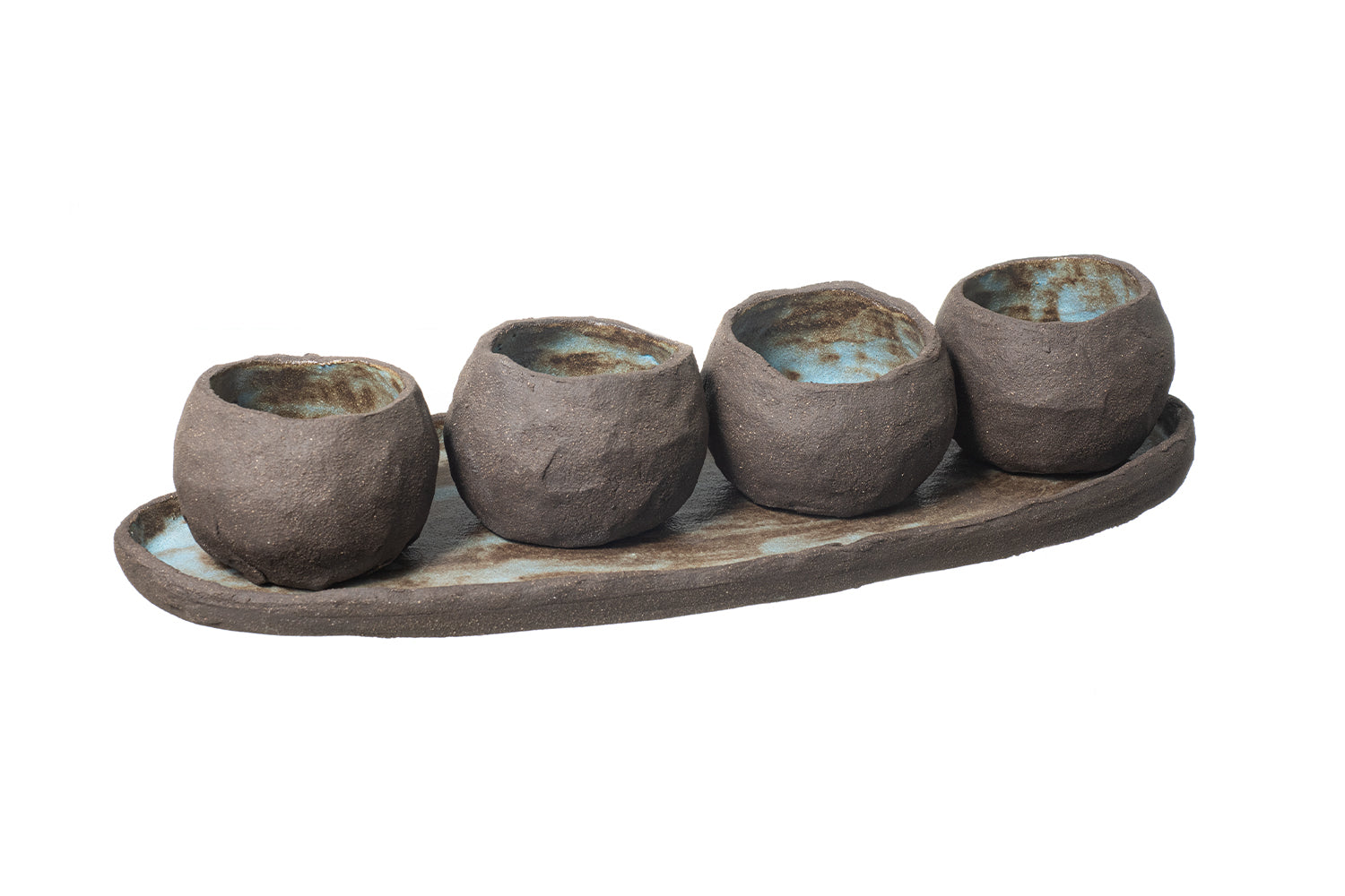 The ATLANTIS platter and bowls set features four rustic, asymmetrical ceramic cups with a rough brown exterior and blue-green interior, displayed on an oval handmade stoneware platter against a white background.
