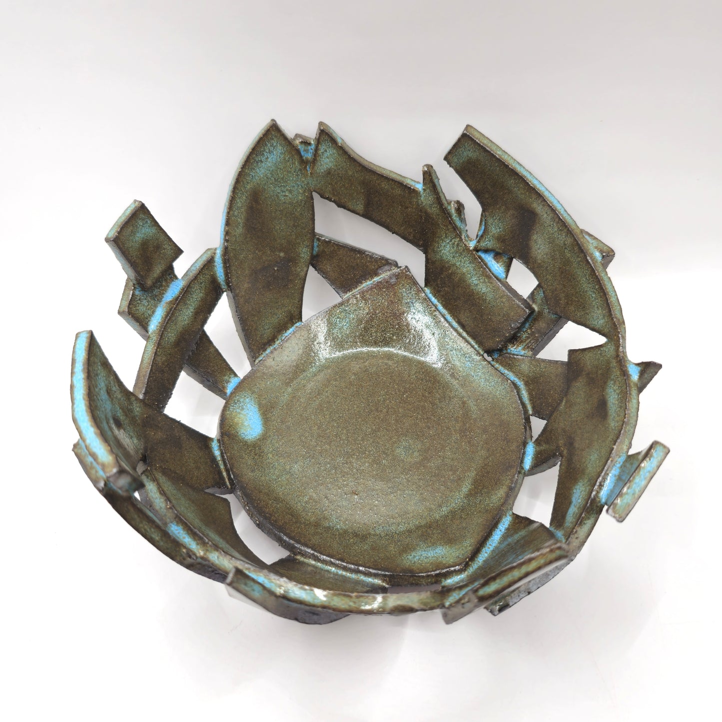 The ATLANTIS 'BRUTE' BOWL is a handmade stoneware piece with an abstract, irregular form, jagged overlapping edges, a smooth center, and a metallic iridescent glaze over black clay for a bold, modern look.