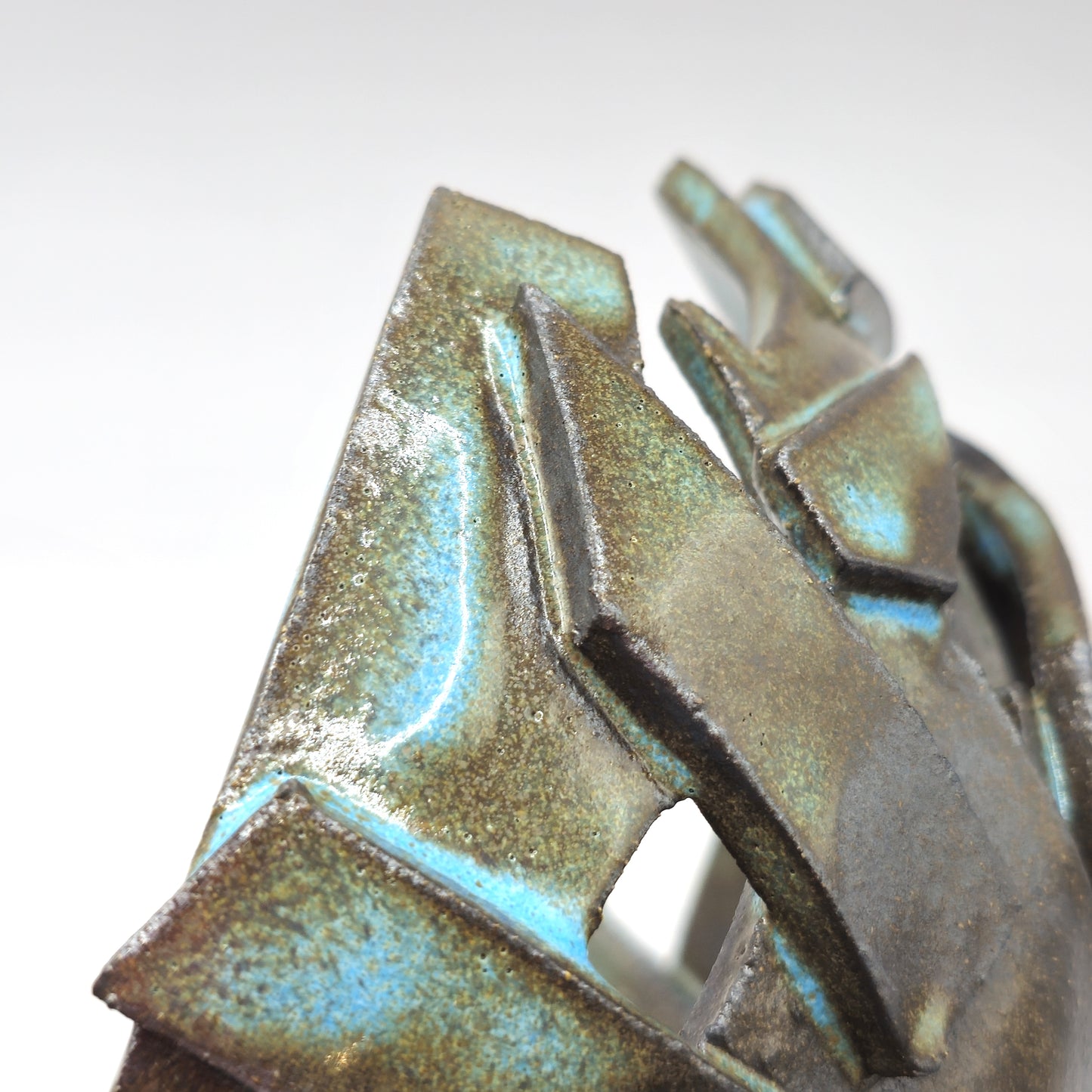 Close-up of the ATLANTIS 'BRUTE' BOWL, an abstract ceramic piece with angular, layered forms in brown and greenish-blue glazes, crafted from handmade stoneware and black clay, displayed against a plain white background.