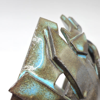 Close-up of the ATLANTIS 'BRUTE' BOWL, an abstract ceramic piece with angular, layered forms in brown and greenish-blue glazes, crafted from handmade stoneware and black clay, displayed against a plain white background.
