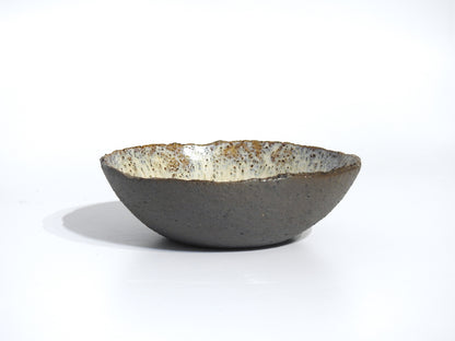The STONE SOUP BOWL is a handmade ceramic piece featuring a textured brown exterior and a speckled, glazed white interior, ideal for serving meals straight from your small frying pan. Shown on a plain white background.