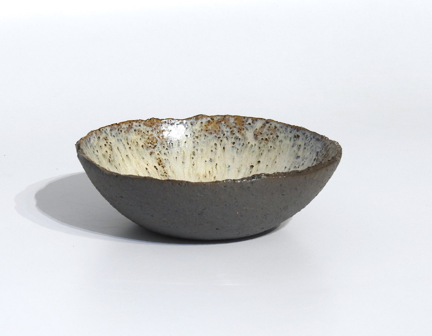 The STONE SOUP BOWL features a handmade ceramic design with a rough gray exterior and smooth, white-speckled interior—an elegant 18 cm alternative to a traditional pan for serving or plating, shown against a plain white background.