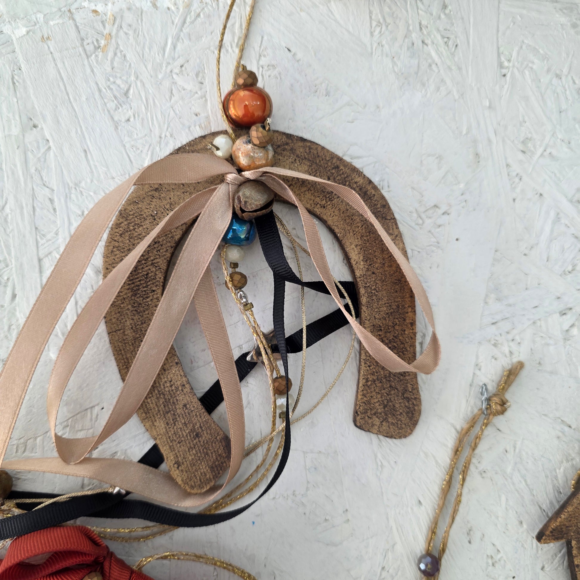 Decorative item with ribbons and beads on a textured white surface