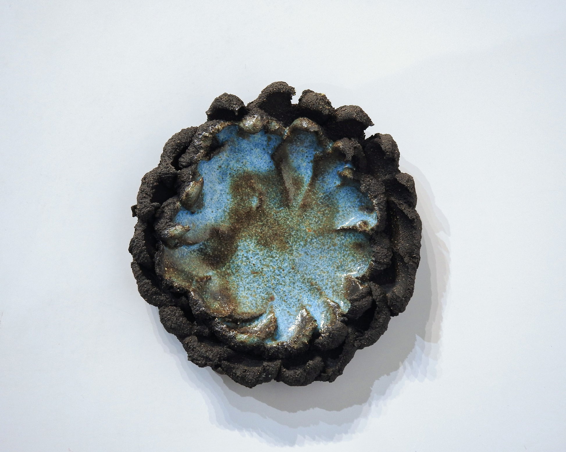 Ceramic ashtray with blue glaze and textured brown rim 
