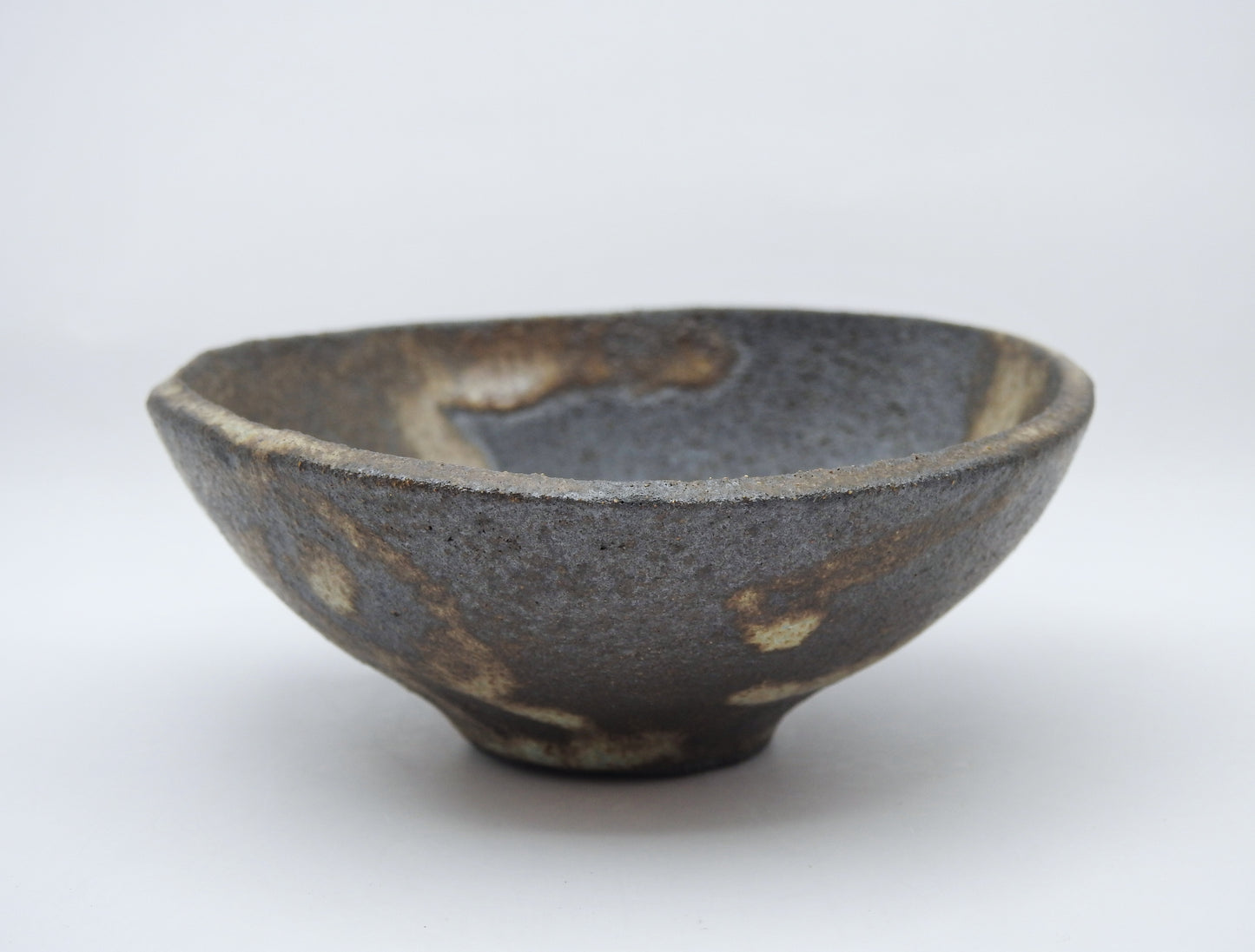 The SOIL SMALL DIP BOWL is a handmade stoneware ceramic bowl featuring a rough gray surface with earthy brown and white patches, shown against a plain white background.