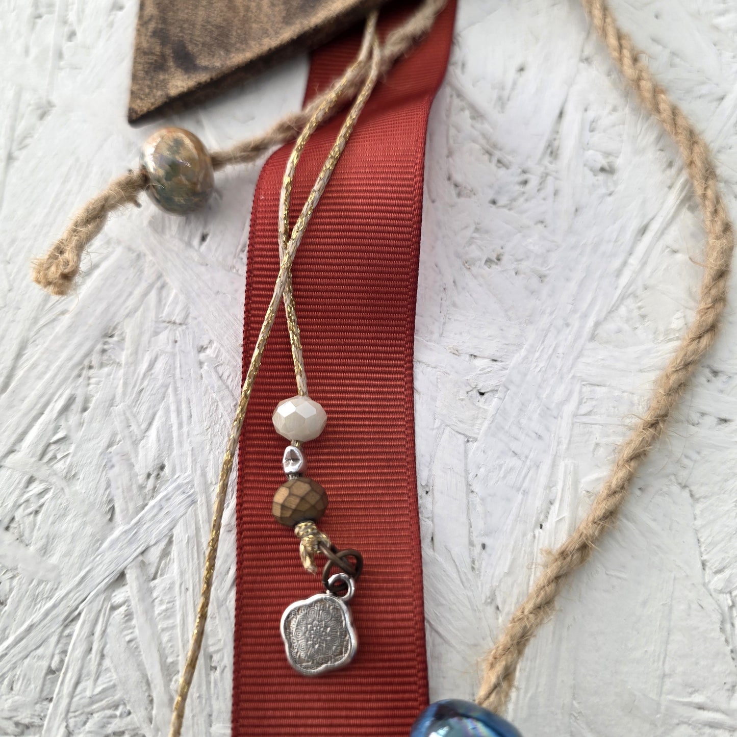 ceramic with beads and pendants on a textured white surface